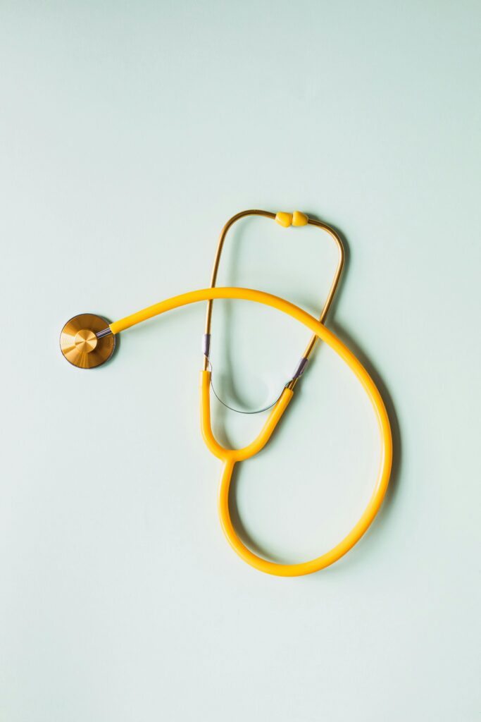 Top view of yellow medical stethoscope placed on white surface .